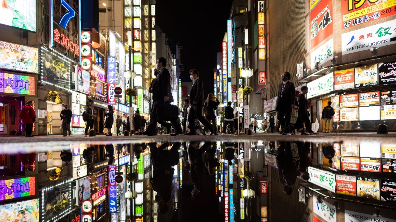 People walk through the famed Kabukicho entertainment district of Tokyo on the first night of the government's lifting of a coronavirus state of emergency, October 1. (Image: AP)
