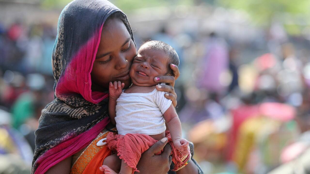 Aameen, a migrant laborer, holds her fifteen-day-old daughter Aradhana, as she waits at a railway station to return to her hometown, in Jammu, India, October 21. (Image: AP)