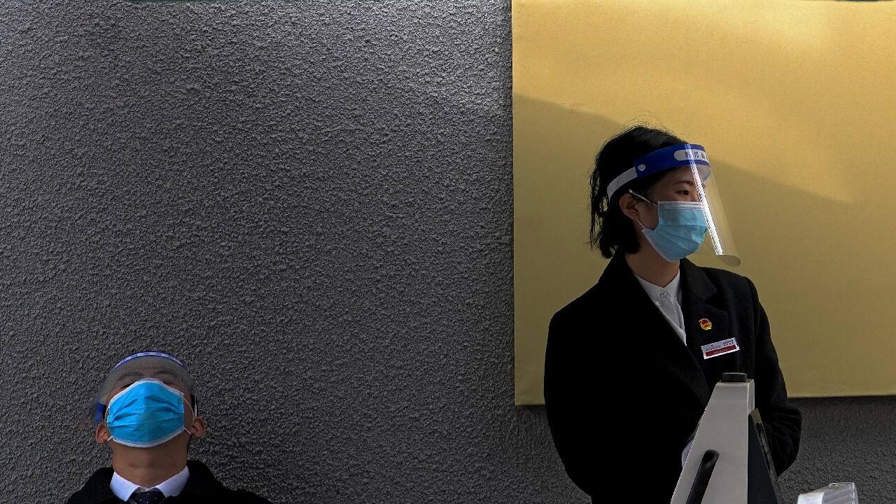 Workers wearing face masks and shields to help curb the spread of the coronavirus wait for visitors outside a museum in Beijing, October 28. (Image: AP)