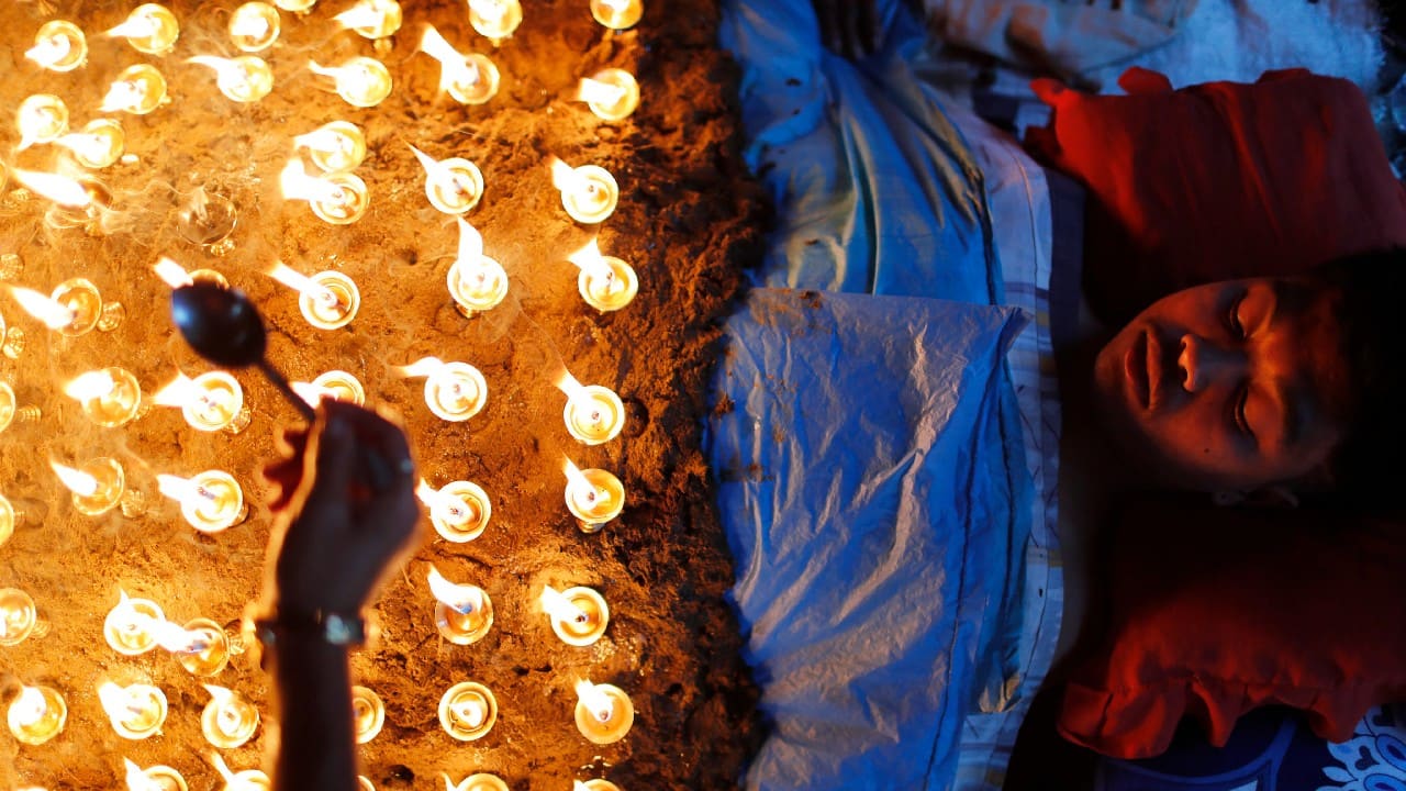 A man lies still as devotees light oil lamps over his body as part of rituals to celebrate the tenth and final day of Dashain festival in Bhaktapur, Nepal, October 15. The festival commemorates the slaying of a demon king by Hindu goddess Durga, marking the victory of good over evil. (Image: AP)