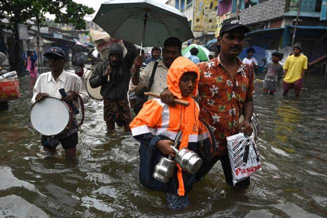 People wade through a flooded street after heavy monsoon rains in Chennai on November 8, 2021. (Photo by Arun SANKAR / AFP)