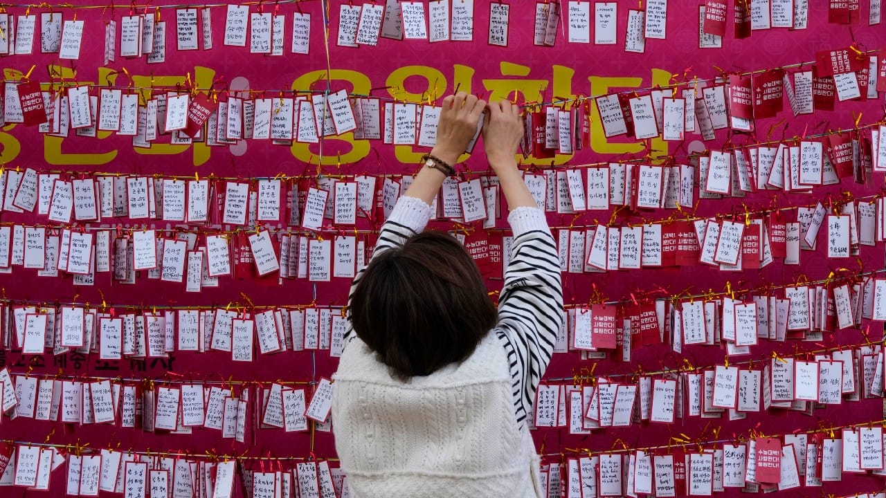 A woman hangs a paper note to wish for her child's success during a special service on the eve of the college entrance exam at the Jogyesa Buddhist temple in Seoul, South Korea, November 17. About 500,000 high school seniors and graduates across the country are expected to take the College Scholastic Ability Test. (Image: AP/Ahn Young-joon)