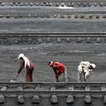Men work inside a coal yard as they clear coal from a railway track on the outskirts of Ahmedabad. (PC-Reuters)