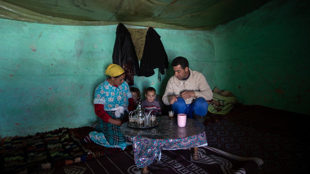 Mohamed Miloud sits in his home as his children are dropped off in a school transport vehicle. A solar panel is perched on top of his brick home as his daughter Ihsan peeks out of the door. “Maybe things will be better for them,&quot; he says. (Image: AP)