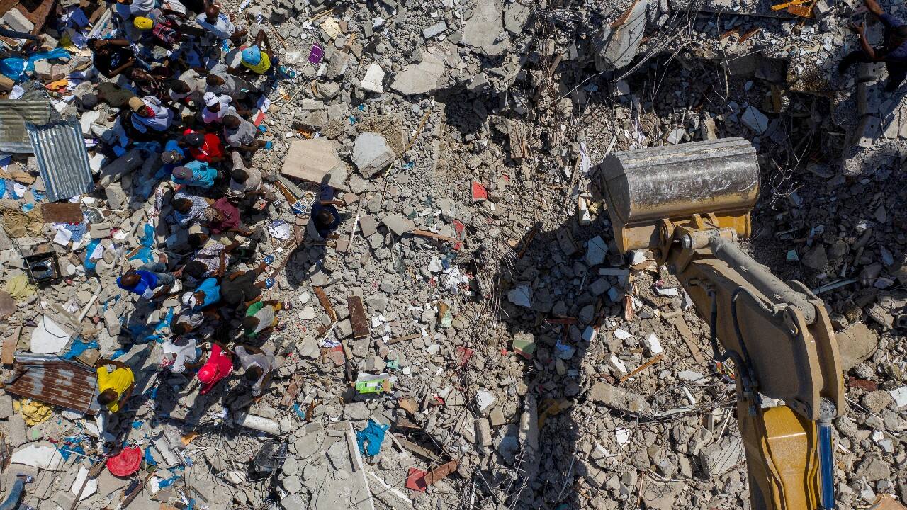 People watch an excavator removing rubble from the site of a collapsed hotel after Saturday's 7.2 magnitude quake, in Les Cayes, Haiti August 16. (Image: Reuters)