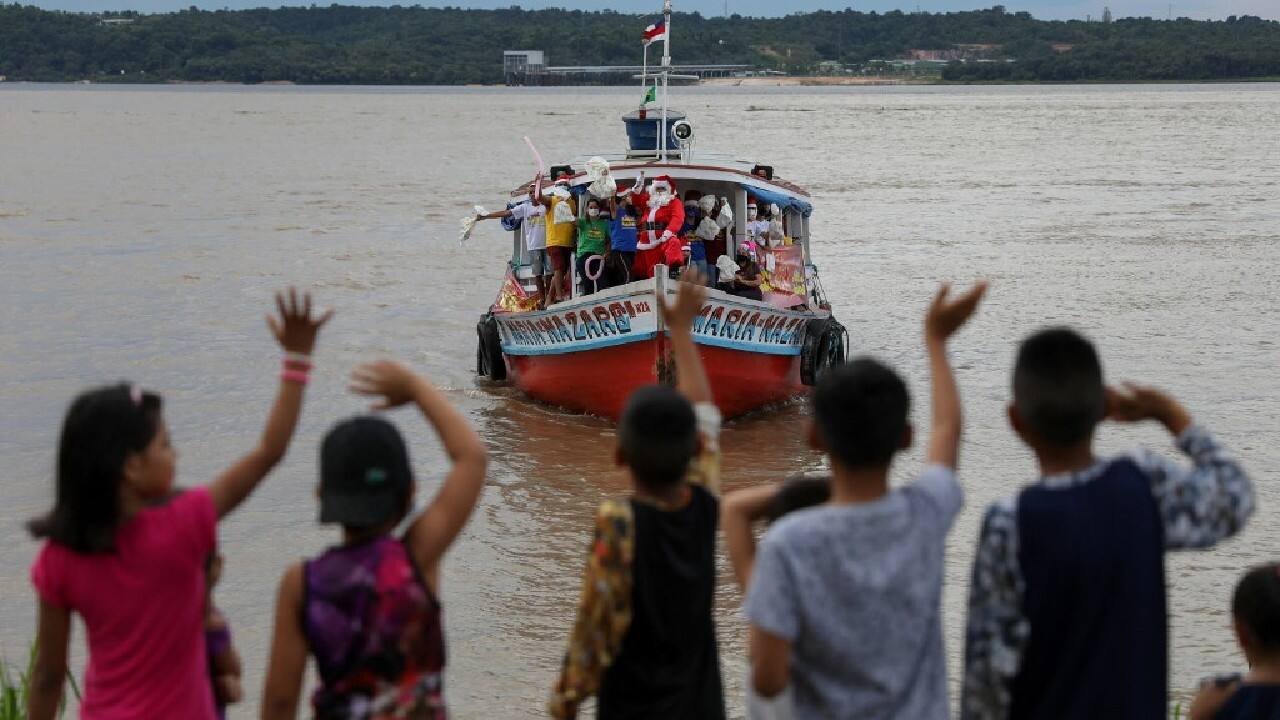 In the heart of Brazil's steaming-hot Amazon region, a sled would be of little use to Father Christmas. Instead, perched on the prow of a rumbling river boat, he waves cheerily to the excited children who wait for him at river's edge. (Image: AFP)