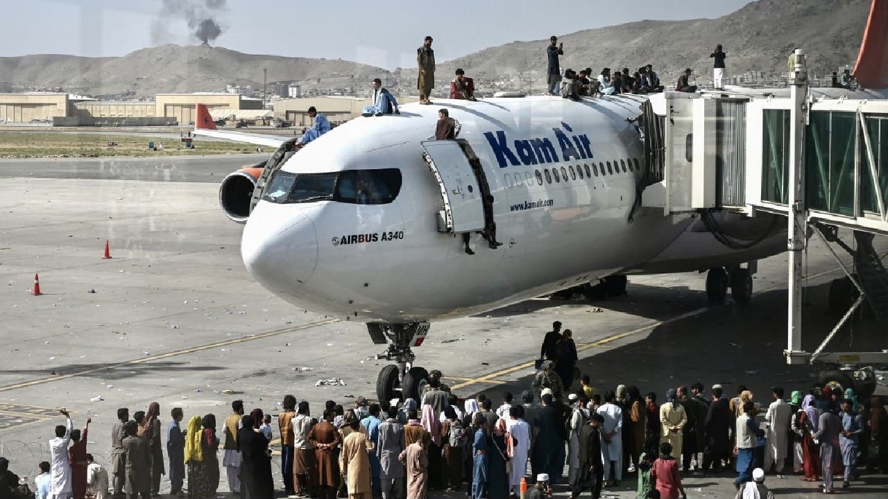 Afghan people climb atop a plane as they wait at the Kabul airport in Kabul on August 16, after a stunningly swift end to Afghanistan's 20-year war, as thousands of people mobbed the city's airport trying to flee the group's feared hardline brand of Islamist rule. (Image: AFP)