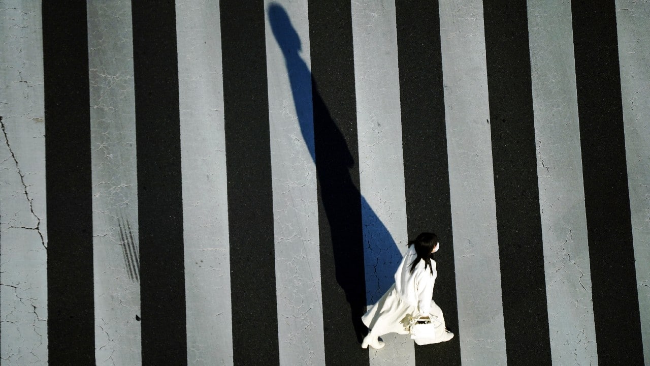 A woman wearing a protective mask to help curb the spread of the coronavirus walks along a pedestrian crossing on December 29, in Tokyo. (Image: AP)