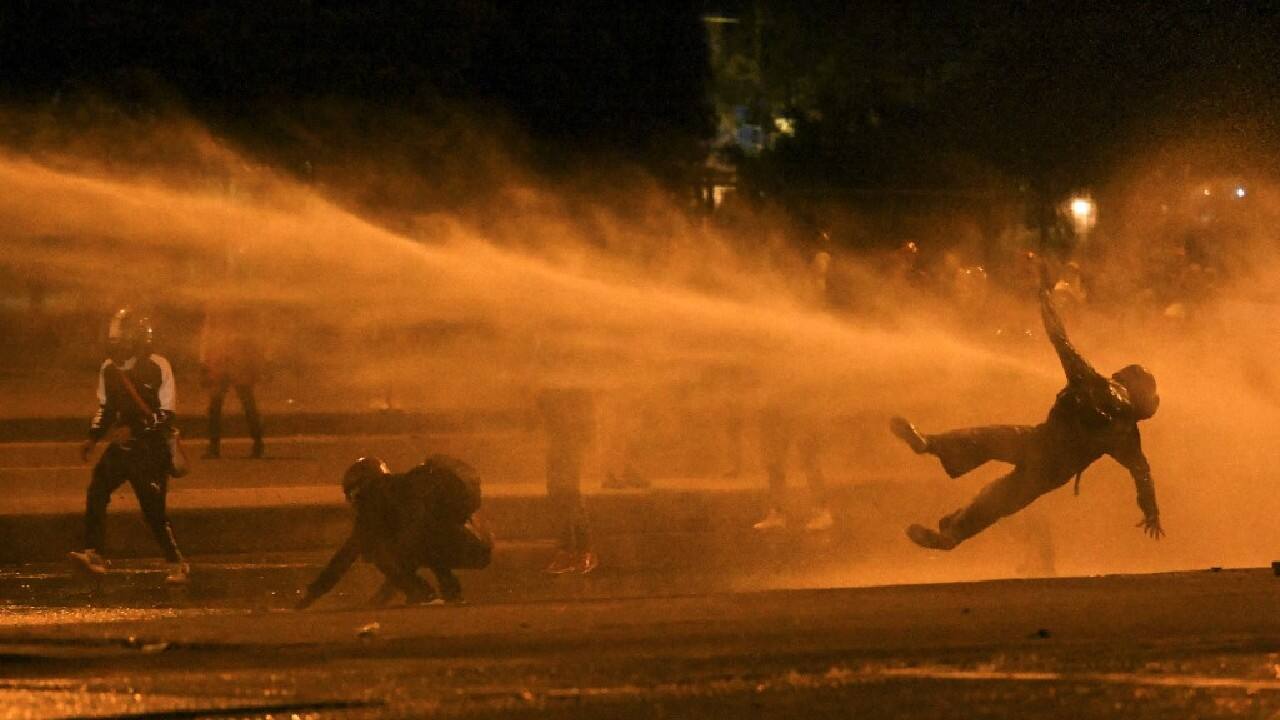 A demonstrator falls as they are hit by water cannon during clashes with riot police amid ongoing protests against the government of Colombian President Ivan Duque in Bogota on June 12. Dozens of people have been killed in protests that erupted around the country on April 28, initially against a tax hike that would have mostly affected the middle classes, but which have morphed into a major anti-government movement. (Image: AFP)