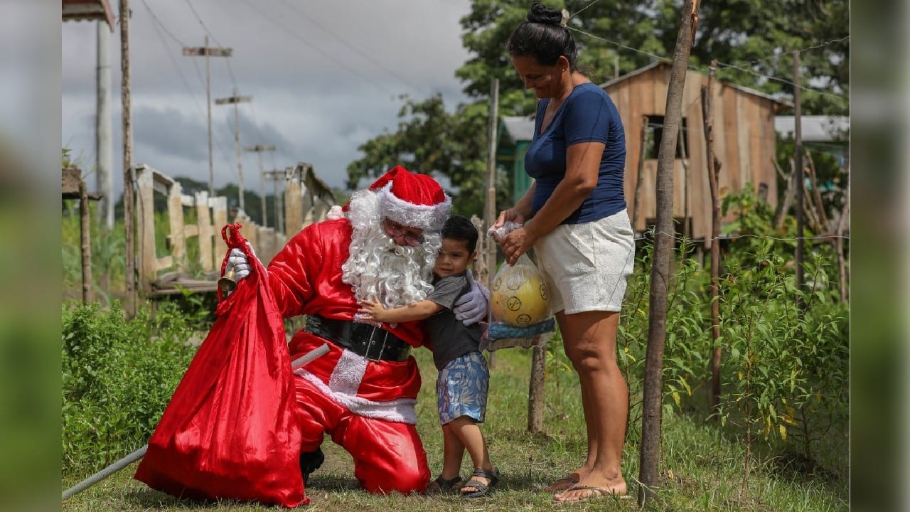 When he finally sets foot ashore after a three-hour journey, this Not-Your-Average-Santa does what Santas do everywhere, opening his arms to greet the giddy children who run up to meet him. (Image: AFP)