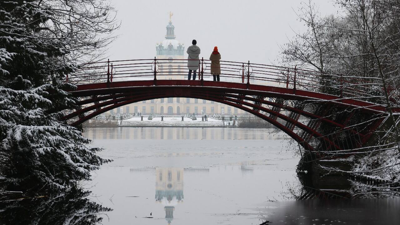 People stand on a bridge of Charlottenburg castle at a snow covered park in Berlin, Germany. (Image: Reuters)