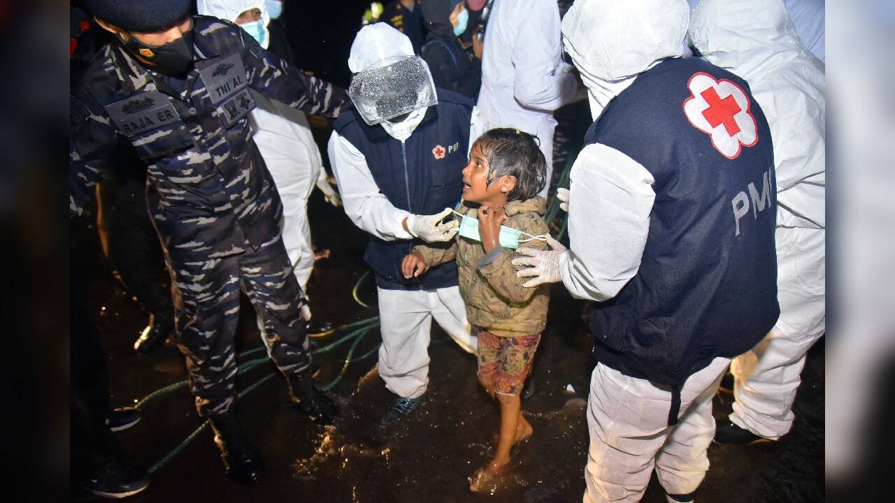Medical workers help a Rohingya young girl upon arrival at Krueng Geukueh Port in North Aceh, Indonesia, December 31, 2021. A group of 120 Rohingya Muslims disembarked from a boat that had drifted for days off Indonesia's northernmost province of Aceh and was towed by a navy ship into port, officials said Friday. (Image: AP)