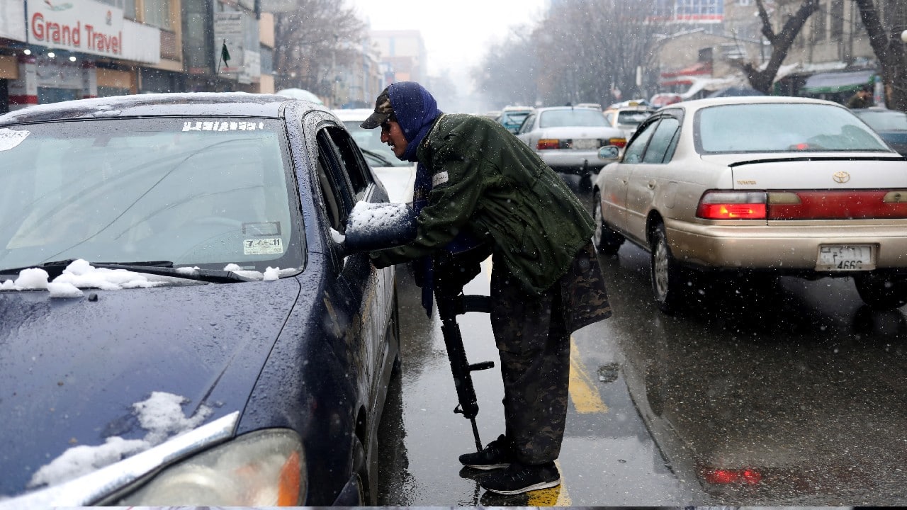 A Taliban fighter searches a car as he stands guard at a checkpoint during a snowfall in Kabul, Afghanistan, January 3. (Image: Reuters)
