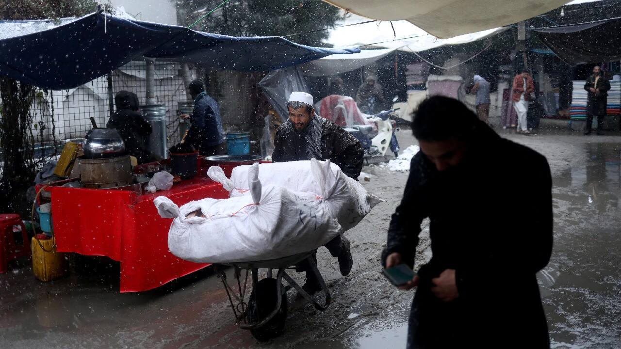 An Afghan man pushes his wheelbarrow in a market during a snowfall in Kabul, Afghanistan, January 3. (Image: Reuters)