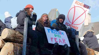 Protestors sit on a trailer carrying logs as truckers and supporters take part in a convoy to protest coronavirus disease (COVID-19) vaccine mandates for cross-border truck drivers in Ottawa, Ontario, Canada. (Image: Reuters)