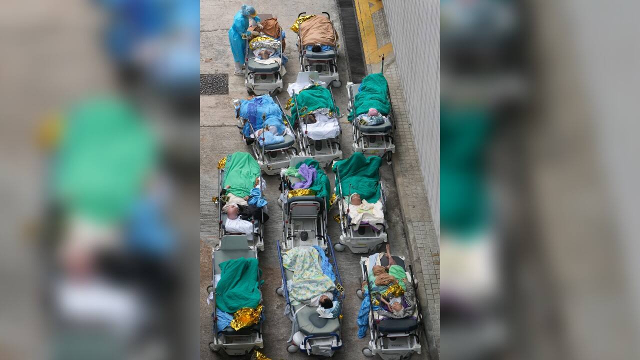Patients lie on hospital beds as they wait at a temporary holding area outside Caritas Medical Centre in Hong Kong, February 16. There was visible evidence that Hong Kong hospitals were becoming overwhelmed by the latest COVID surge, with patients on stretchers and in tents being seen to by medical personnel on Wednesday outside the Caritas hospital. (Image: AP)