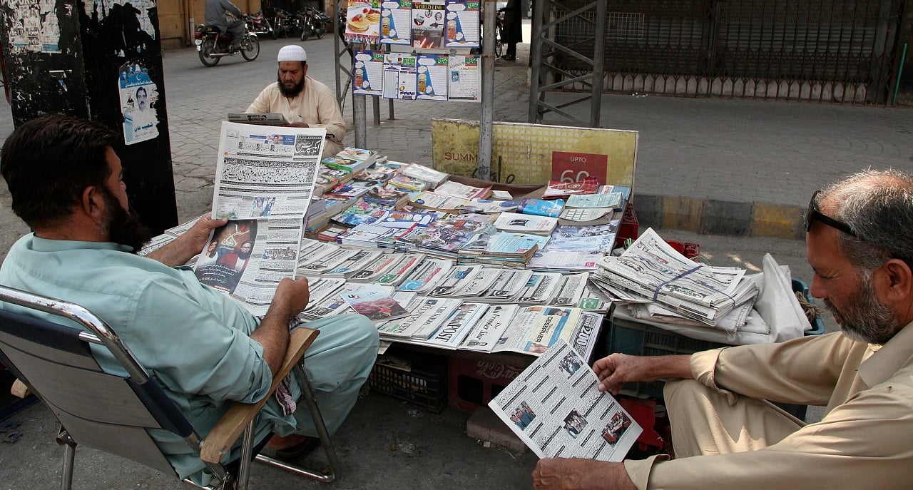 People read copies of newspapers carrying headline of the Supreme Court decision against Imran Khan's move to dissolve the assembly, at a stall in Peshawar on Friday, April 8, 2022 (AP Photo/Muhammad Sajjad)
