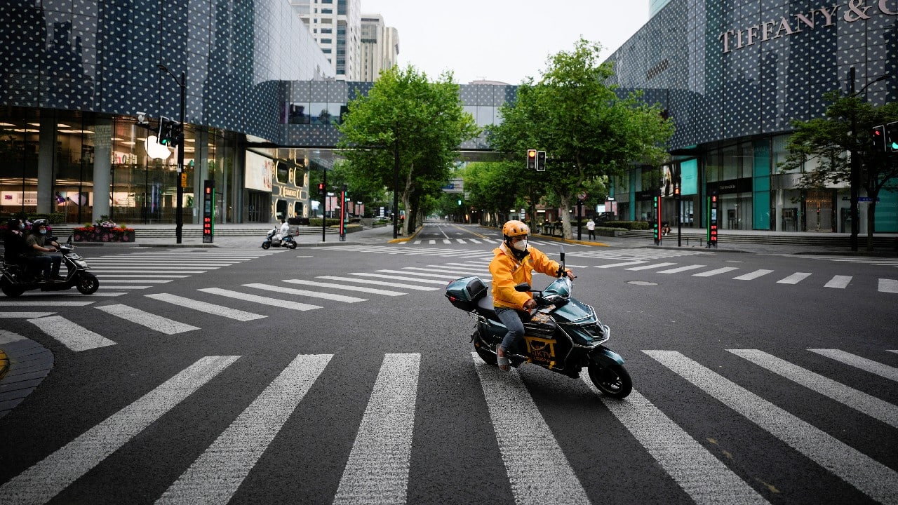 A delivery worker rides an electric scooter across a main shopping area during lockdown, amid the coronavirus pandemic, in Shanghai, China, May 26. (Image: Reuters)