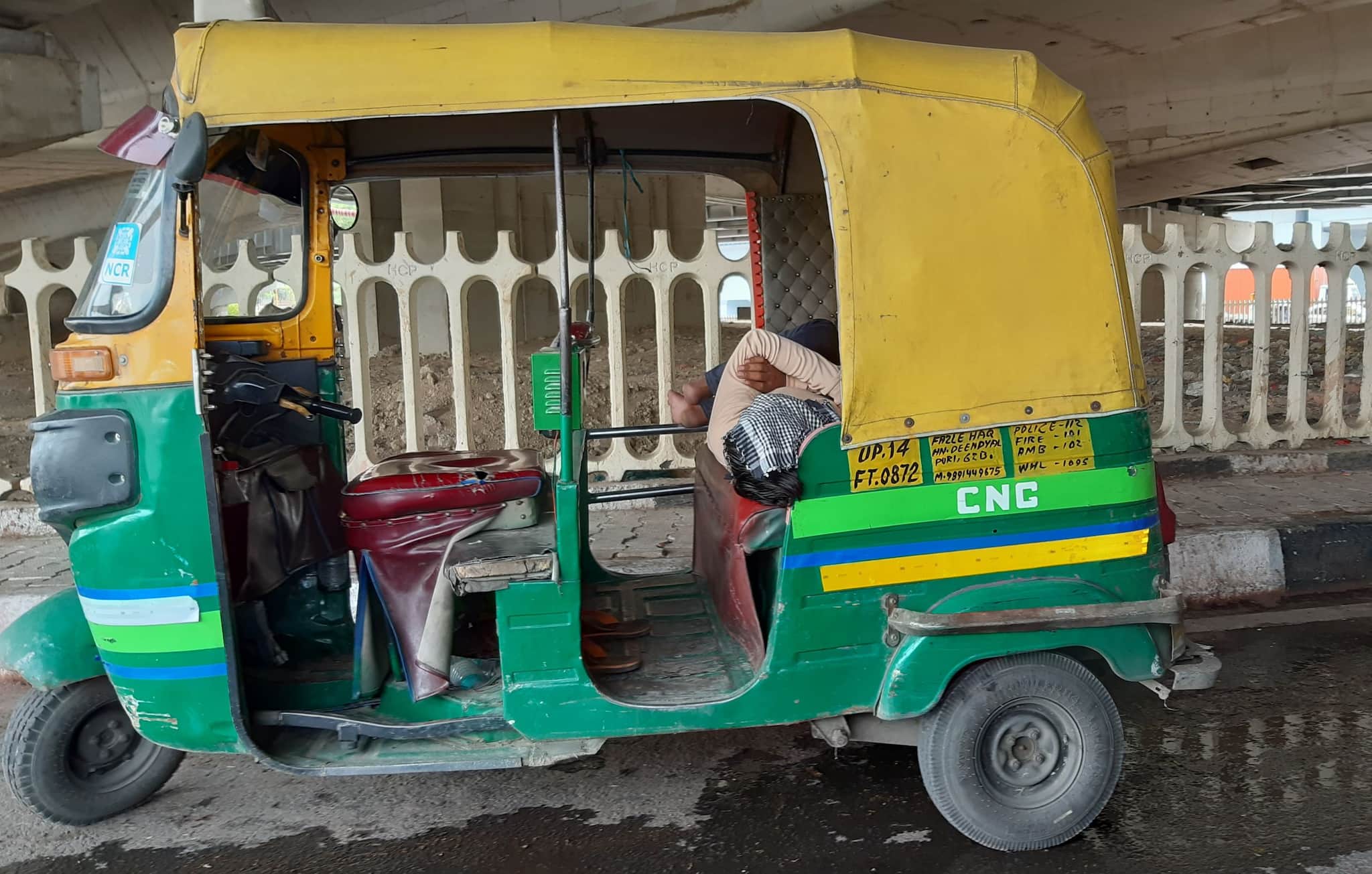 Parked under a flyover in Delhi to escape the head, an auto driver takes a nap. 