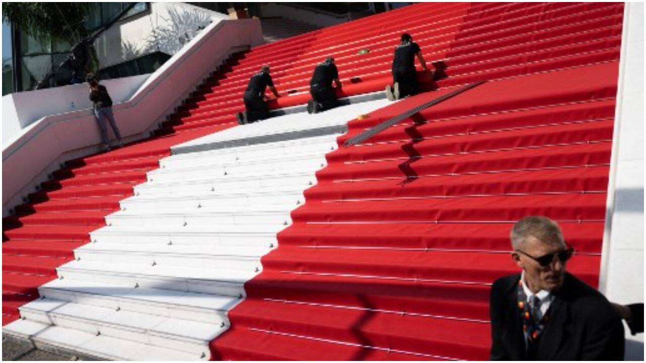 Festival staff roll the red carpet as the 75th edition of the Cannes Film Festival kicks off in southern France, on May 17, 2022. 