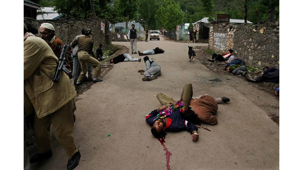 An Indian policeman lies dead among other civilians on the street outside an election rally venue seconds after a grenade explosion in border town Uri, 102 kms north of Srinagar, April 8, 2004. At least 11 persons were killed and 60 were wounded, including two government ministers, in the suspected rebel attack on a People's Democratic Party's (PDP) election rally. (Photograph and caption by Altaf Qadri)