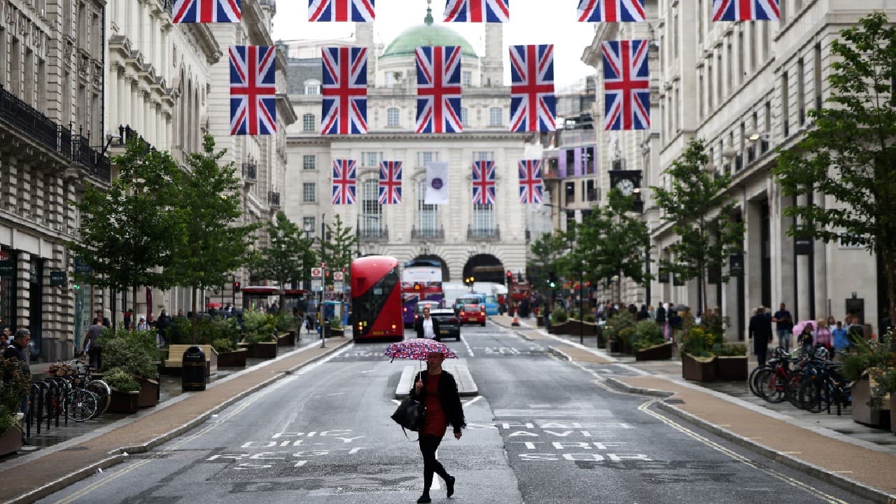 A person holding an umbrella walks underneath rows of Union Jack flags hanging across Regent Street in London, Britain, May 30. (Image: Reuters) (With inputs from Reuters)
