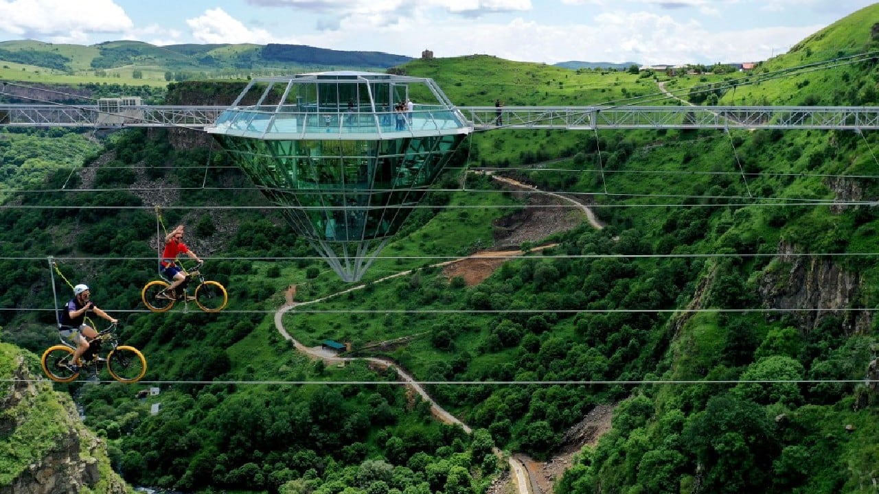 People ride bikes on a zip line next to a 240-meter long glass bridge over the Tsalka canyon, with a diamond-shaped cafe in the middle outside the city of Tsalka, some 100 km from Tbilisi. (Image: AFP)