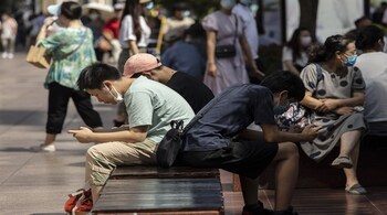 Teenagers play games on their phone while sitting on a bench at Nanjing Road East in Shanghai, China, on Sunday, Oct. 3, 2021. China contained its latest Covid-19 outbreak just in time for a week-long holiday that started on Oct. 1, avoiding the need for travel curbs during a crucial period of consumer spending and domestic tourism. Photographer: Qilai Shen/Bloomberg