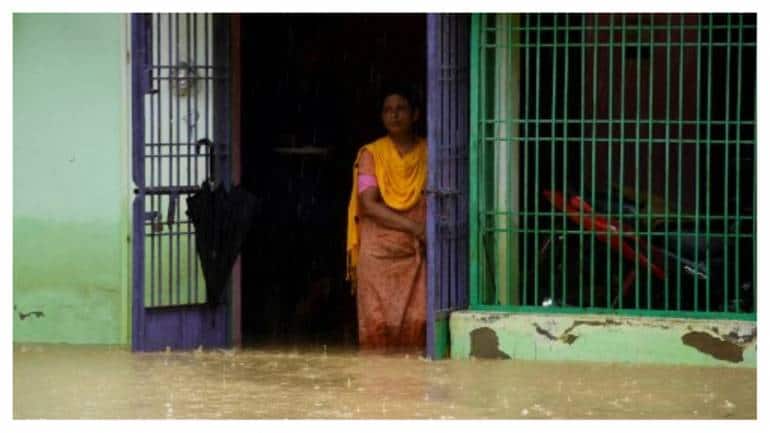 A woman looks out from the front door of her flooded home following heavy rainfalls in Kampur, in India's Assam state on June 17, 2022.
