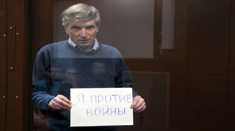 Alexei Gorinov holds a sign “I am against the war” standing in a cage during hearing in the courtroom in Moscow, Russia, (AP Photo/Alexander Zemlianichenko)(Alexander Zemlianichenko / Associated Press)