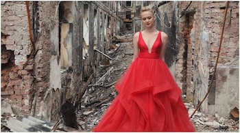 A teenager from Ukraine poses for a photo in front of her destroyed school. (Image: @avalaina/Twitter)