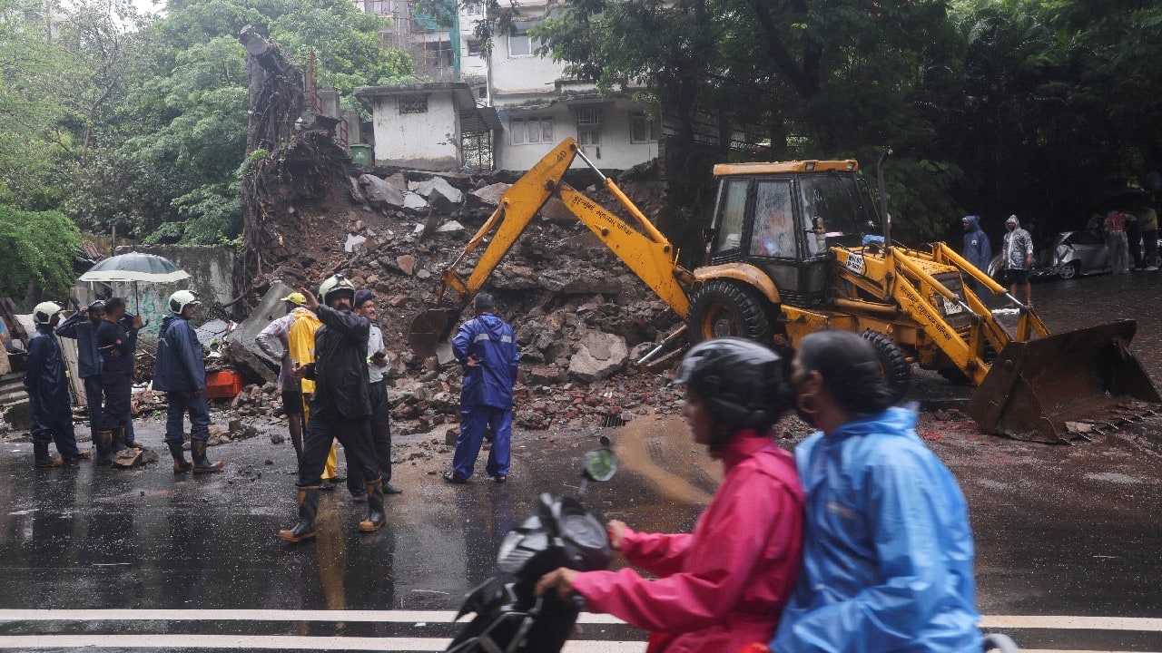 Fire fighters clear the debris after a wall of a residential building collapsed amidst heavy rainfall in Mumbai. (Image: Reuters)