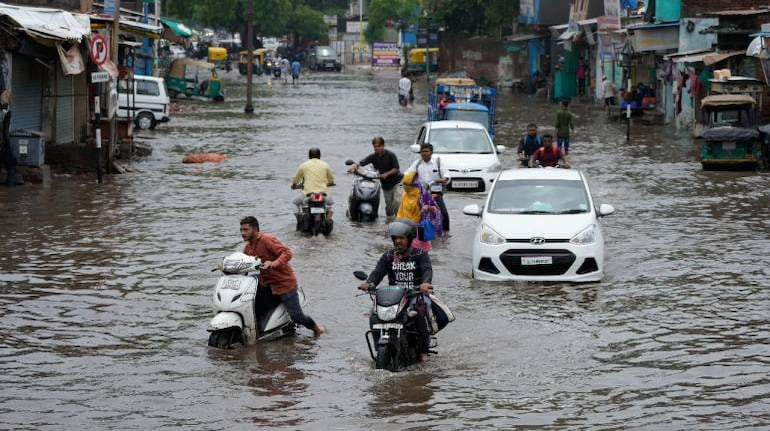 Commuters move through a waterlogged road after heavy rain lashed city on Sunday night in Ahmedabad. (Image: AP)