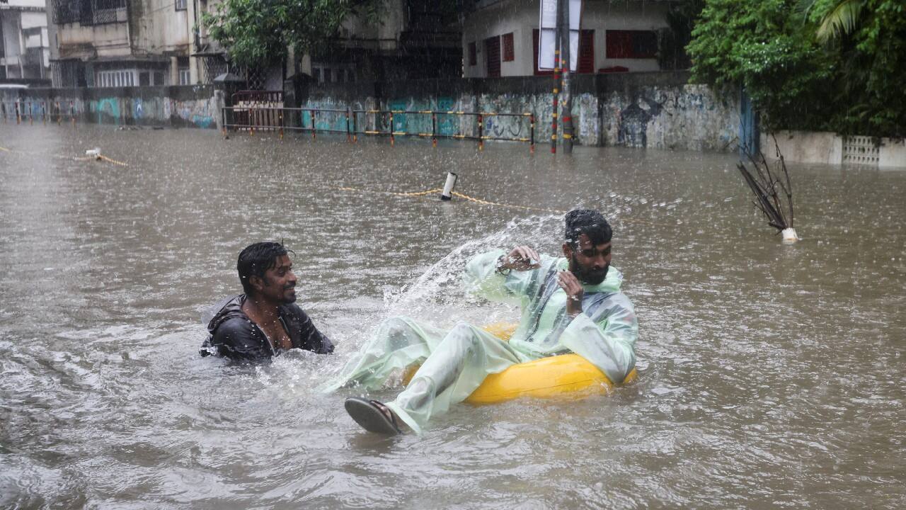 A man splashes water on another amidst heavy rainfall on a flooded street in Mumbai. (Image: Reuters)