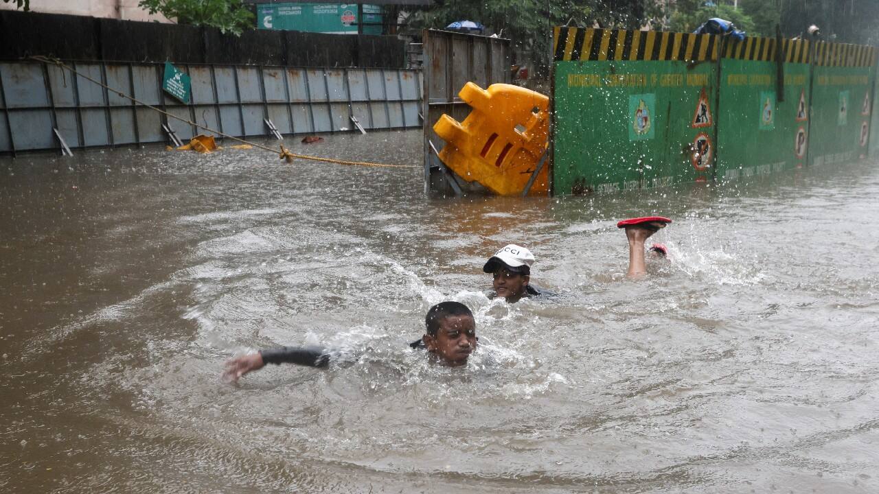Boys swim on a flooded street amidst heavy rainfall in Mumbai. (Image: Reuters)