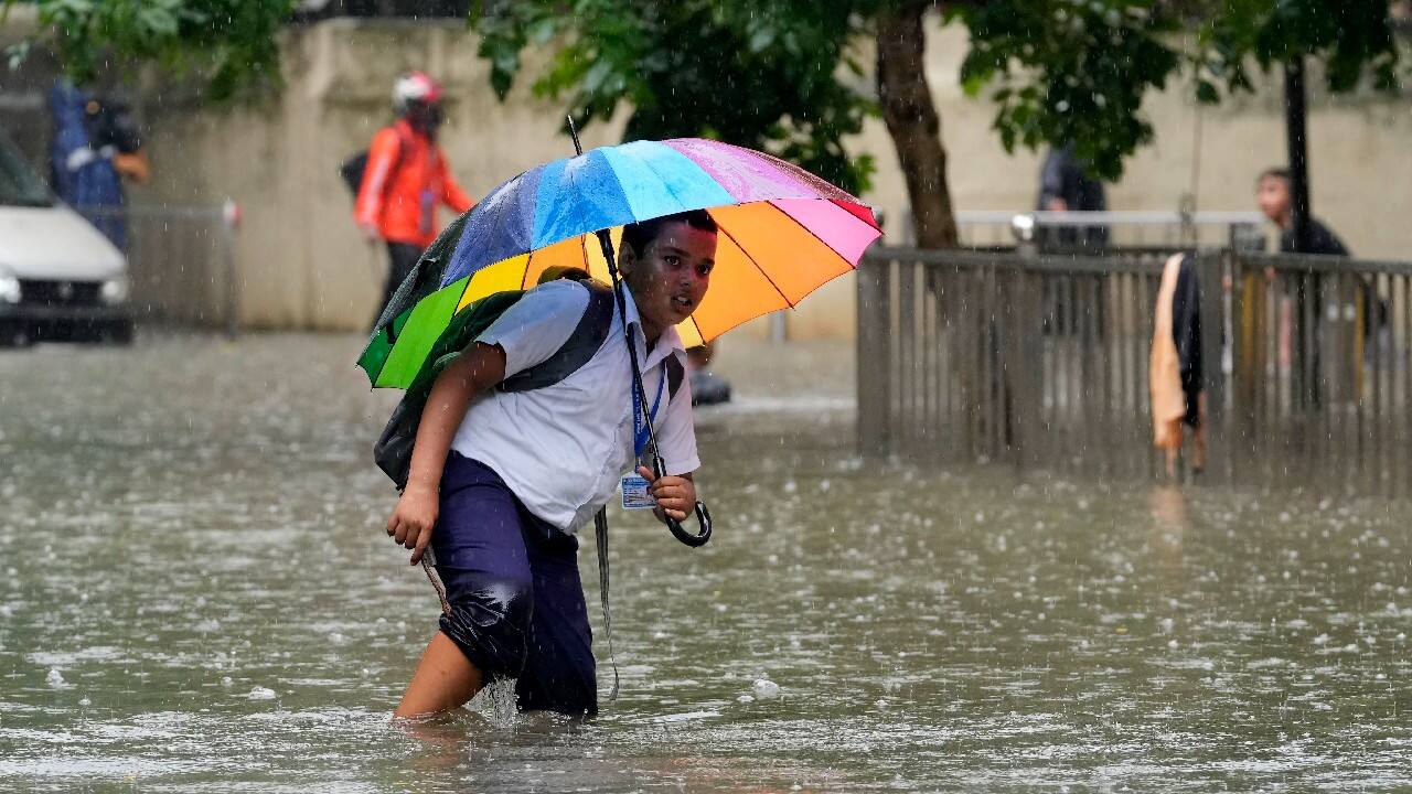 A schoolboy wades past a water logged street during heavy rainfall in Mumbai. (Image: AP)