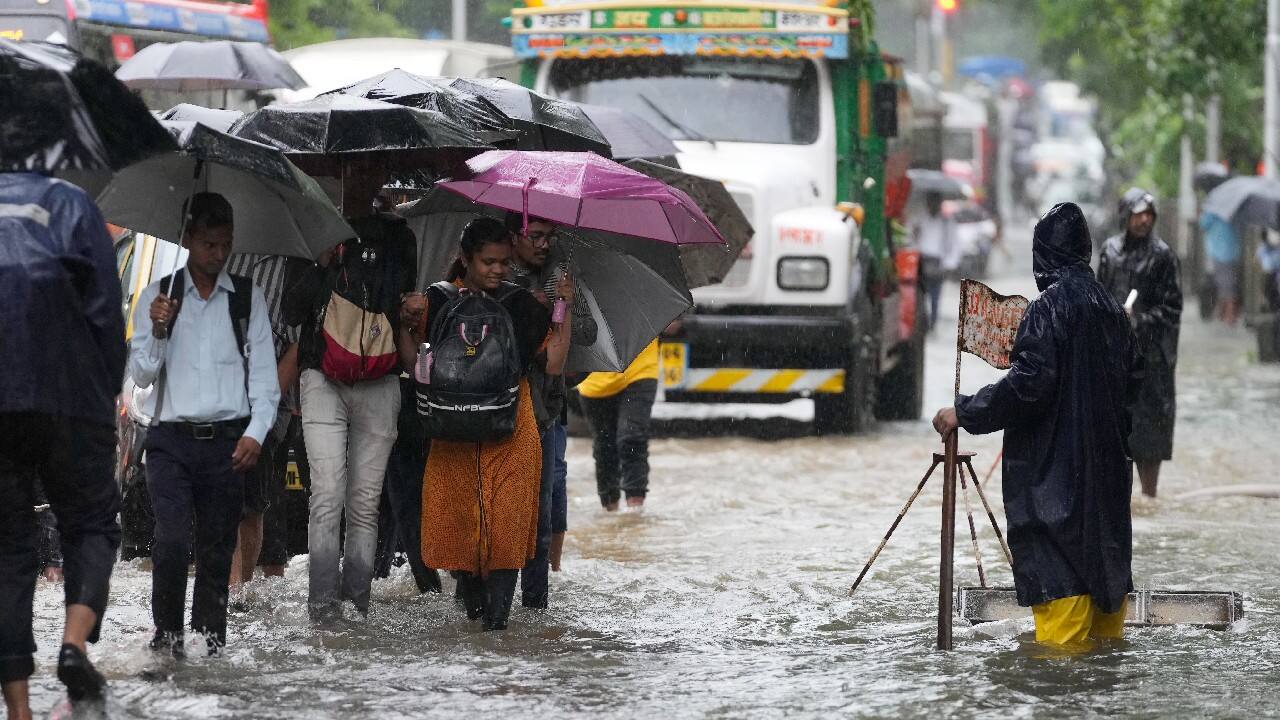 People wade past a waterlogged street during heavy rainfall in Mumbai. (Image: AP)