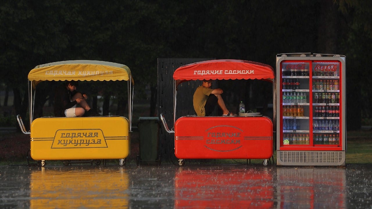 Vendors sit on kiosks as they take cover from heavy rain near the Northern River Station in Moscow, Russia July 25. (Image: Reuters)
