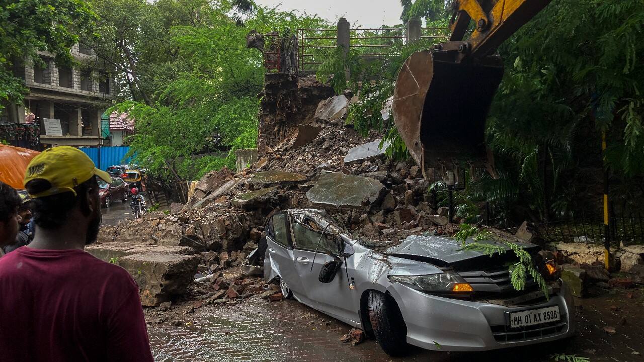 A crane works to move a car damaged after a wall collapsed during heavy rainfall in Mumbai. (Image: AP)