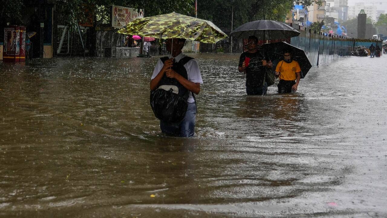 People wade past a waterlogged road during heavy rainfall in Mumbai. (Image: AP)