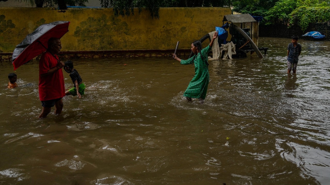 People walk past a waterlogged road during heavy rainfall in Mumbai. (Image: AP)