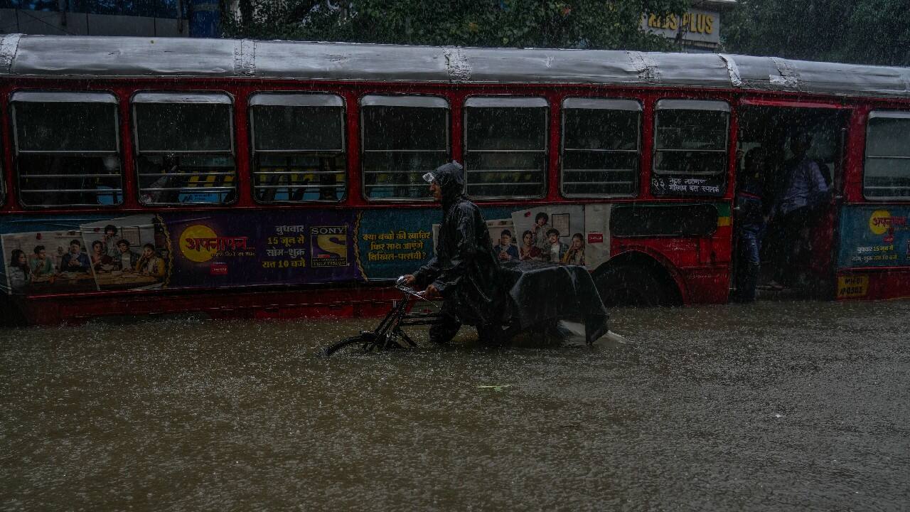 A man pushes his cycle cart past a waterlogged road during heavy rainfall in Mumbai. (Image: AP)