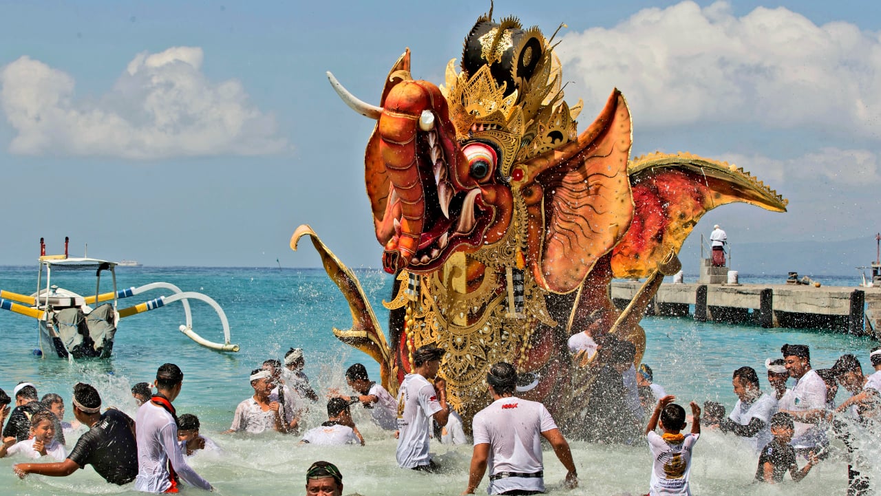 Balinese men parade a giant effigy of a mythical animal which later will be burned during a traditional mass cremation ceremony called &quot;ngaben&quot; on a beach on Friday, July 29, in Padangbai, Bali, Indonesia. Balinese believe that cremating the dead liberates their souls, allowing them to enter the higher world to reincarnate into better beings. 