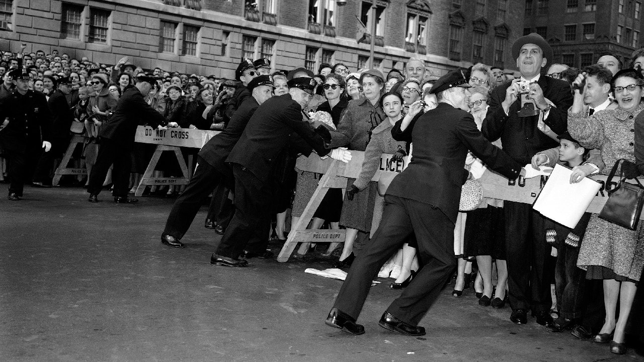 New York City policemen push against police stanchions at Park Avenue and 50th street, New York on October 21, 1957 in effort to contain crowd attempting to view Queen Elizabeth II as she drove to the hotel Waldorf-Astoria. (Image: AP)