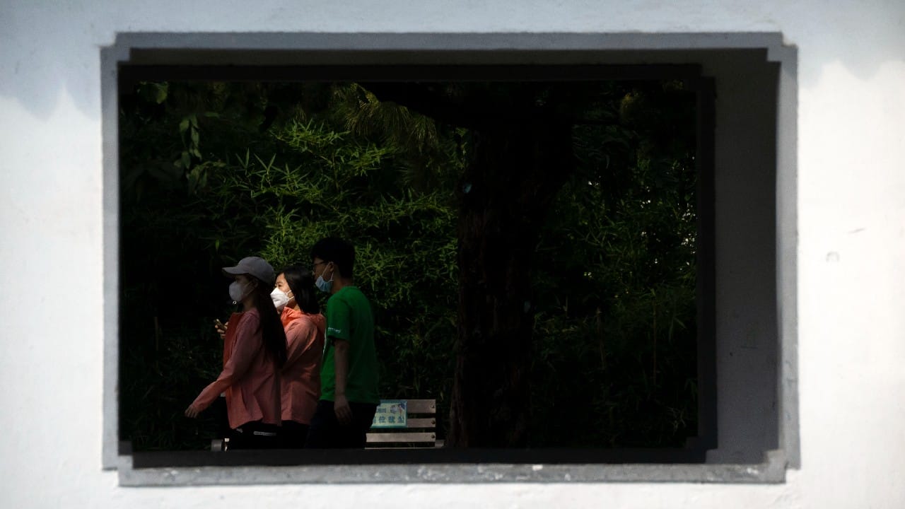 People wearing face masks walk along an exercise path at a public park in Beijing, September 22. (Image: AP)