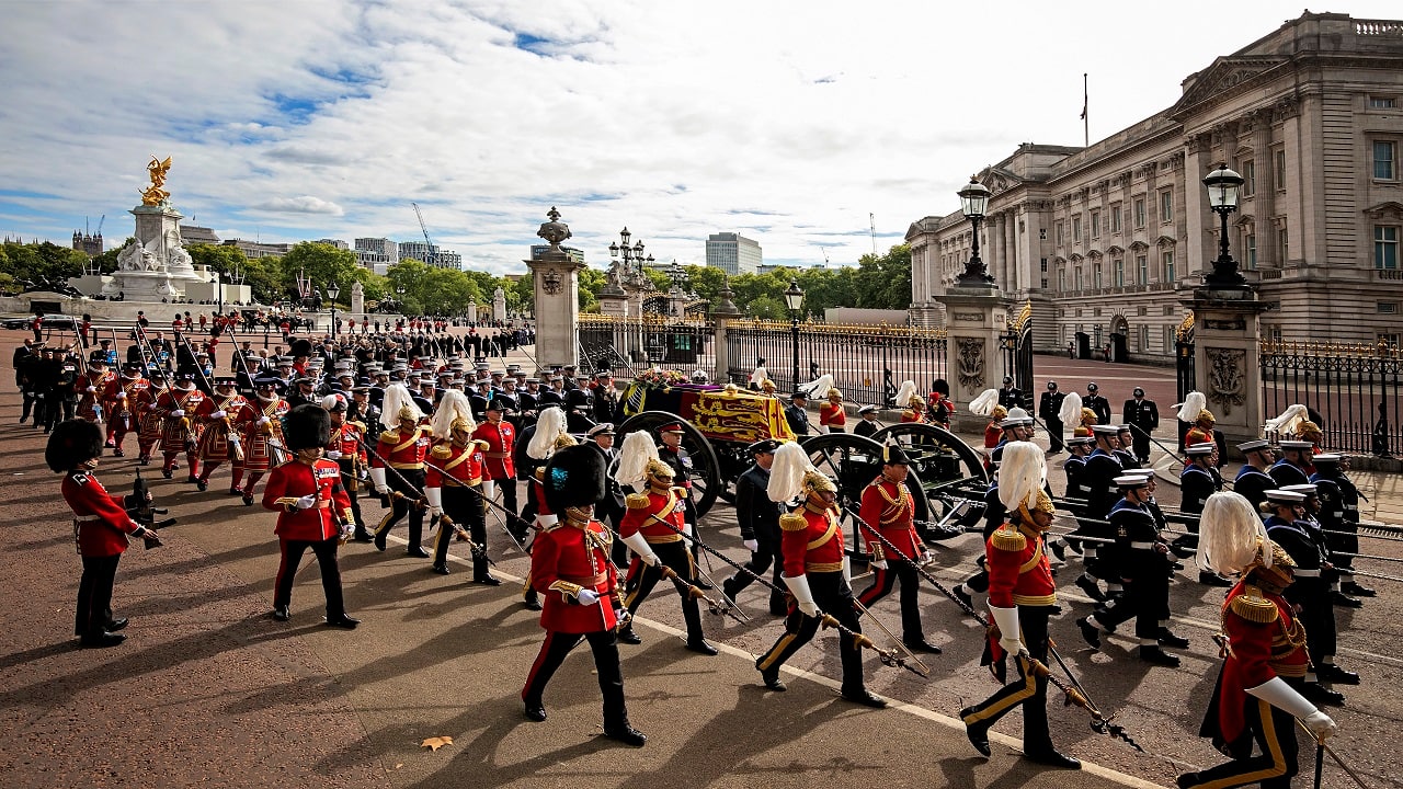 The coffin of Queen Elizabeth II with the Imperial State Crown resting on top, borne on the State Gun Carriage of the Royal Navy proceeds past Buckingham Palace in London, during the state funeral of Queen Elizabeth II, Monday Sept. 19, 2022. The Queen, who died aged 96 on Sept. 8, will be buried at Windsor alongside her late husband, Prince Philip, who died last year. (Jenny Goodall/Pool via AP)
