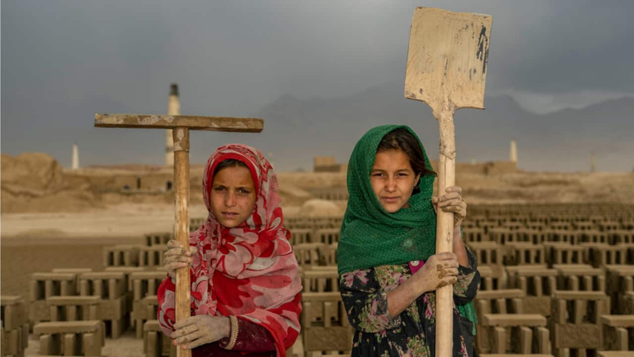 Two Afghan child laborers pose for a photo in a brick factory on the outskirts of Kabul, Afghanistan, Monday, Sept. 12, 2022. Aid agencies say the number of children working in Afghanistan is growing ever since the economy collapsed following the Taliban takeover more than a year ago.