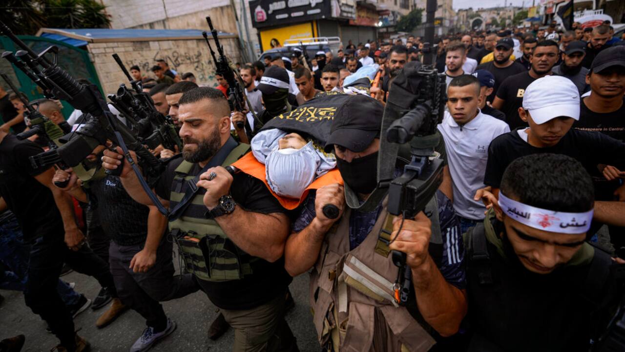 Armed Palestinians carry the body of Mahmoud Al-Sous, covered with a flag of the Islamic Jihad militant group during his funeral in the West Bank town of Jenin.
