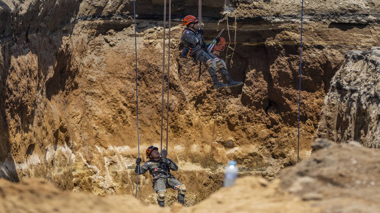 Rescuers from the Guatemalan Army descend into a sinkhole in Villa Nueva, Guatemala, on September 27. Search efforts continued for a mother and daughter who disappeared when their vehicle was swallowed by the massive sinkhole. (Image credit: AP)