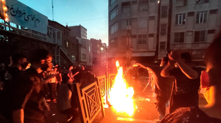 Protesters make fire and block the street during a protest over the death of Mahsa Amini, in downtown Tehran, on September 21. (AP Photo/File)